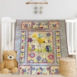 Bird Song in Bloom Baby Quilt on white crib with bear